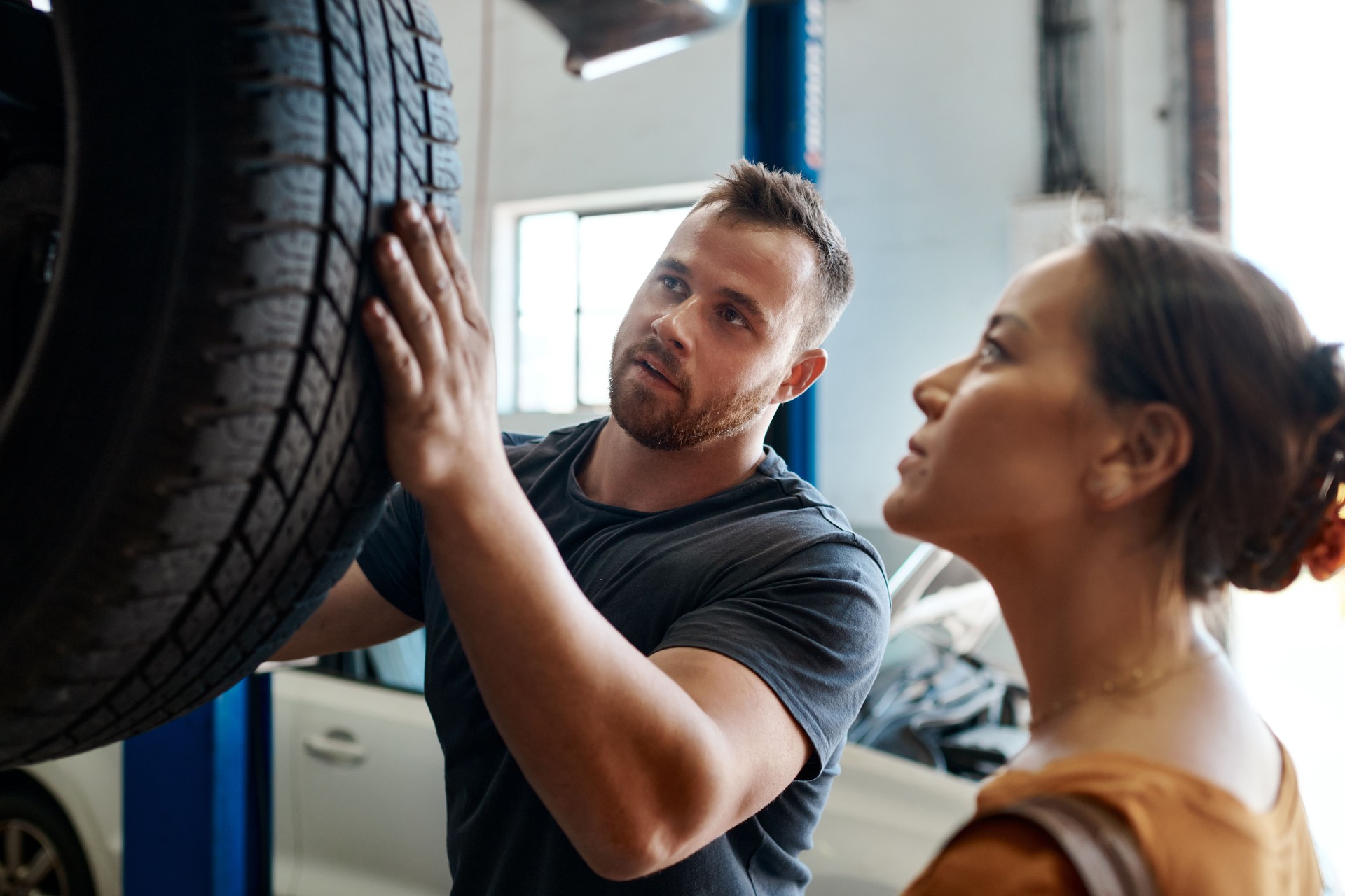 Foto de una mujer hablando con un mecánico en un taller de reparación de automóviles